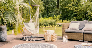 Pillows on hammock on terrace with round rug and rattan sofa in the garden. Real photo