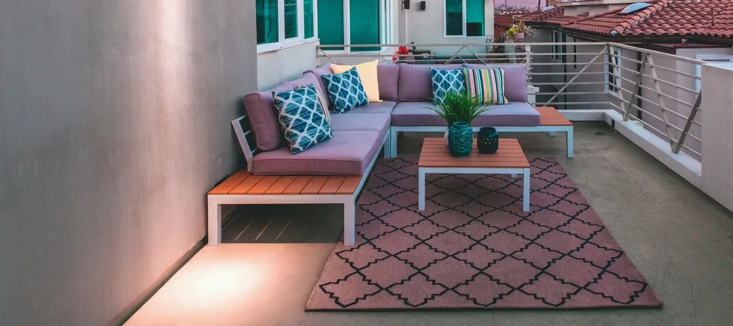 L-shaped outdoor sofa with colorful cushions on a patterned rug in a beautiful outdoor space