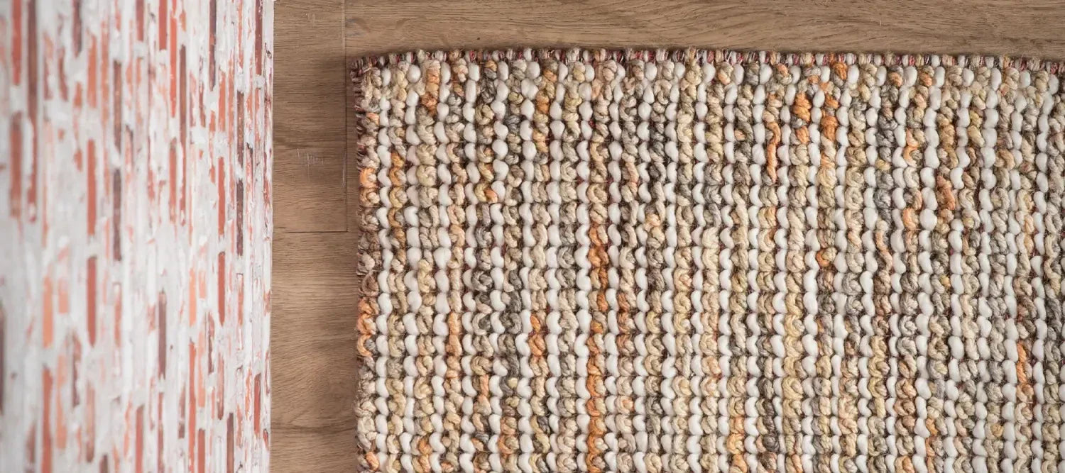 Textured wool rug with chunky knit pattern in neutral and orange tones from leading rugs store