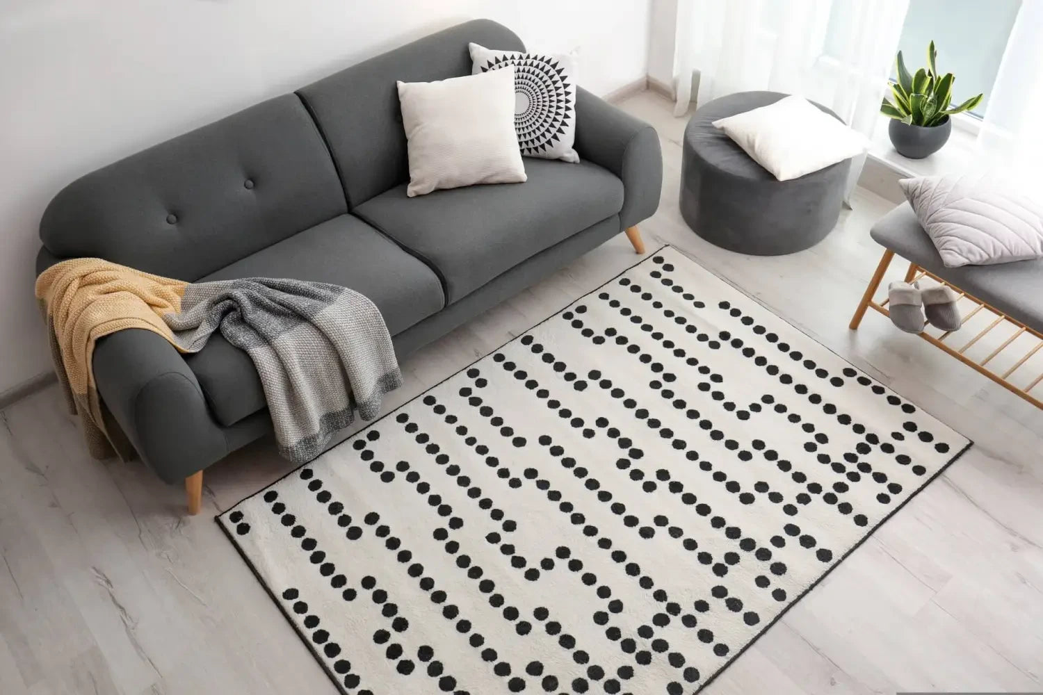 Gray upholstered sofa with tufted back complements layered rugs for a chic look.