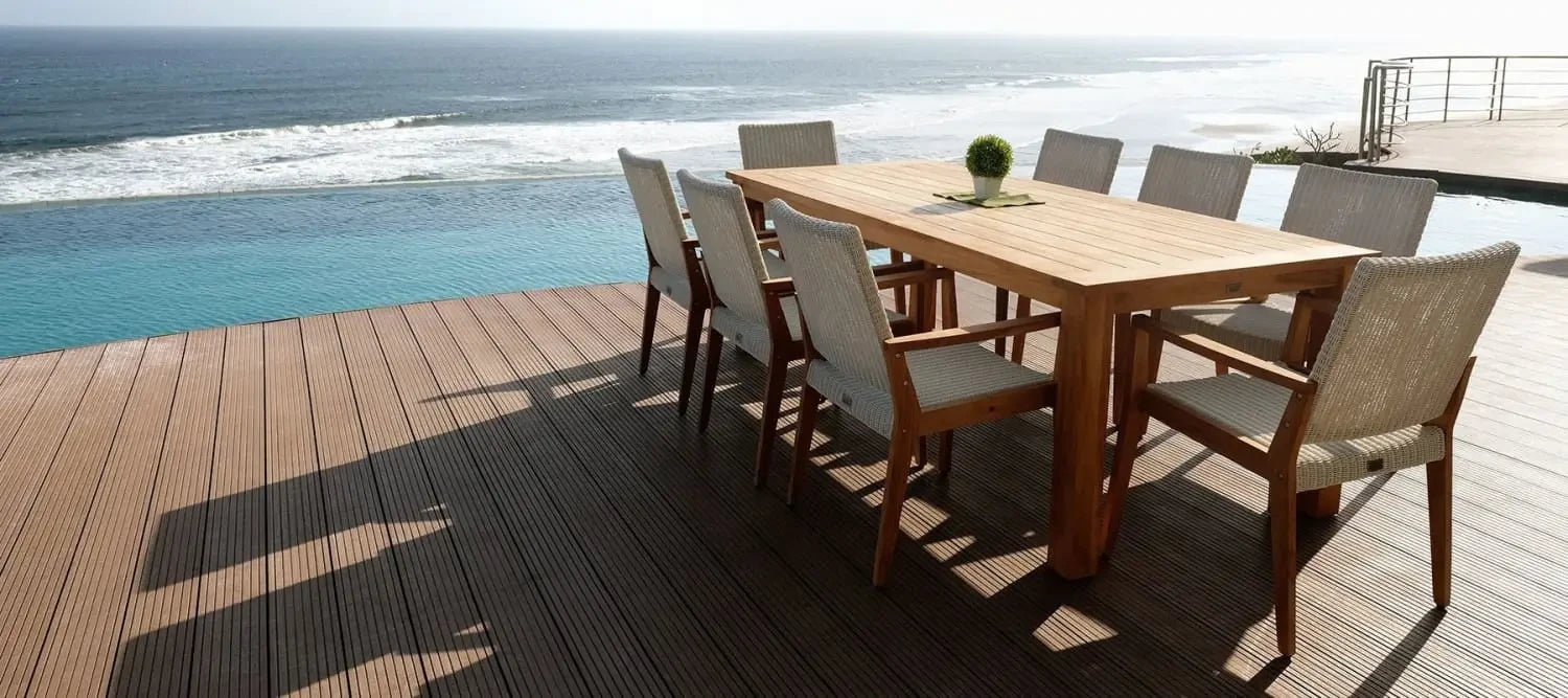 Wooden outdoor dining table and chairs made from teak timber on ocean-view deck