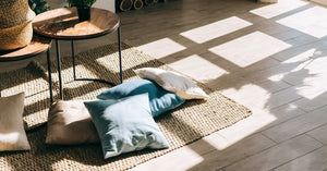 Interior of bright living room in scandinavian style with coffee table and pillows on the floor, big shadow from window on the floor.