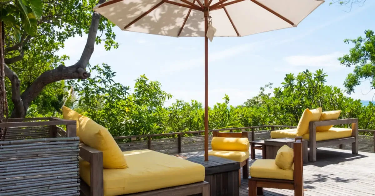 Patio umbrella providing instant shade for outdoor lounge furniture with yellow cushions