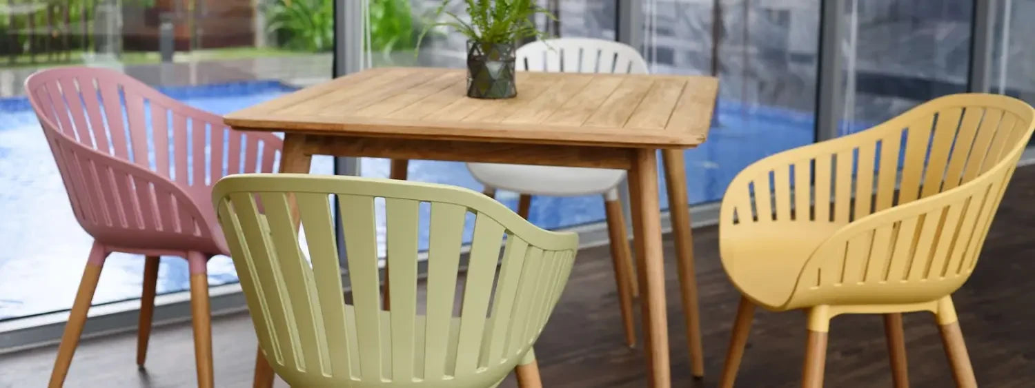 Wooden table with colorful plastic chairs for stylish balcony and bar settings.