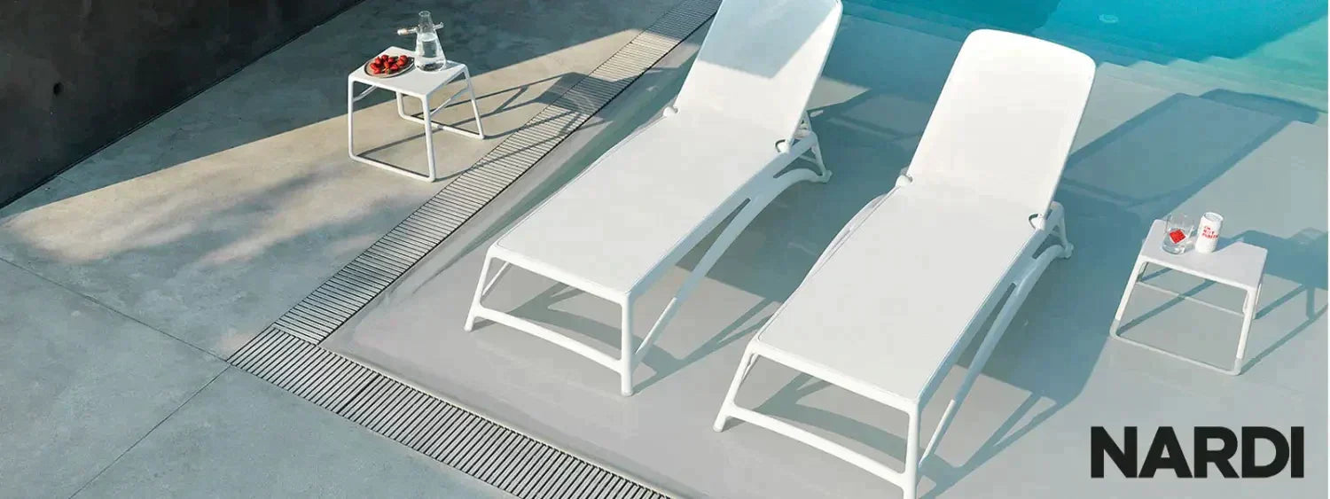 White Nardi Sunloungers with side tables, perfect for relaxation by the pool.