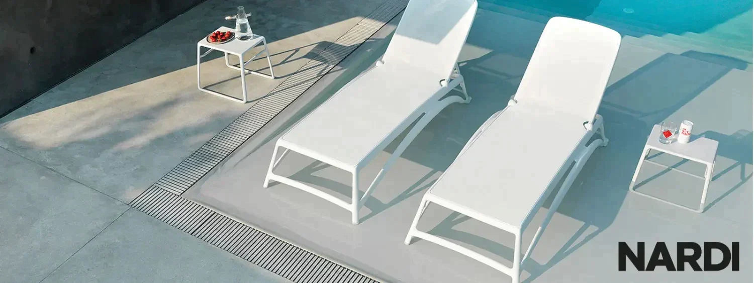 White Nardi Sunloungers with side tables, perfect for relaxation by the pool.
