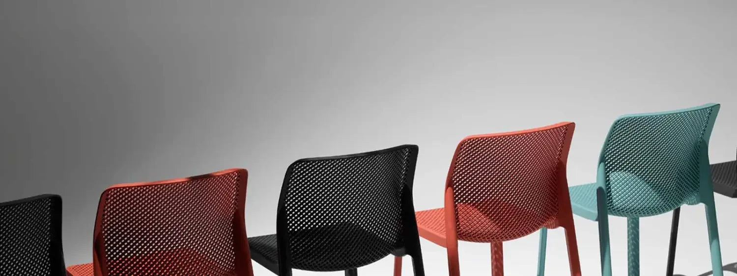 Colorful perforated plastic outdoor bar stools arranged in a vibrant row.